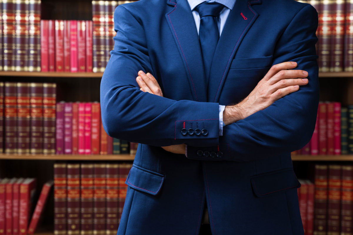 Personal lawyer representing small business stands in front of legal library