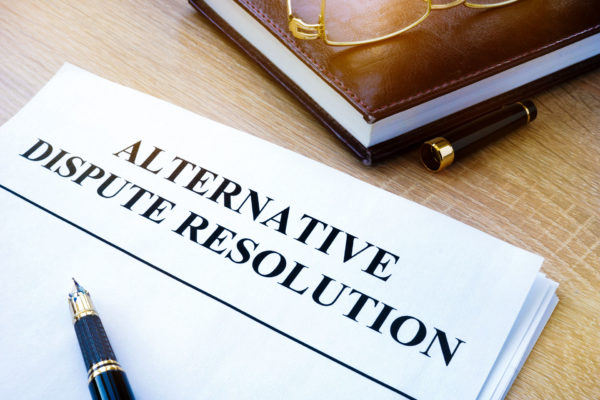 Pen resting atop stack of legal documents titled alternative dispute resolution