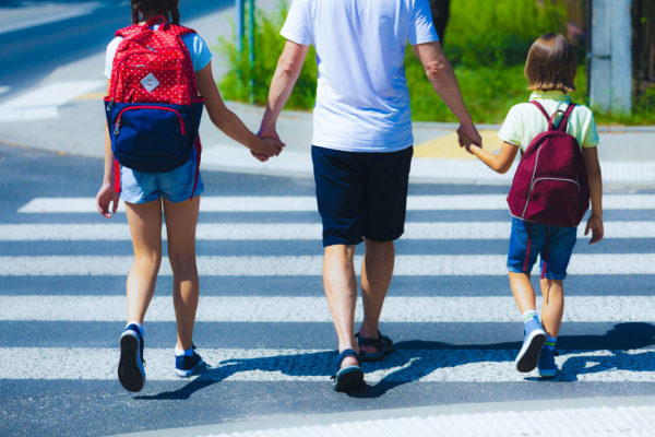 Father teaches responsible children to look both ways before crossing the street