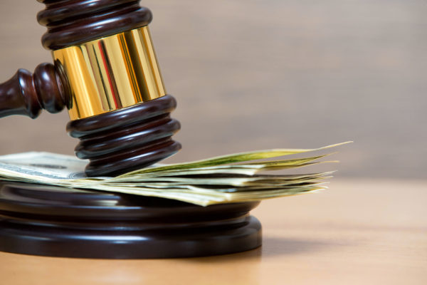 Gavel resting on top of american dollar bills after class action lawsuit