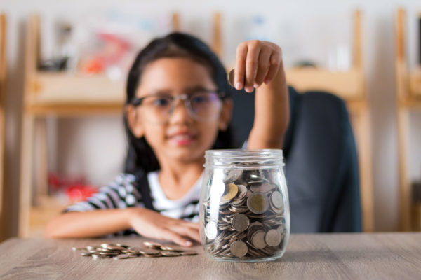 young child participates in family financial tradition of saving spare change