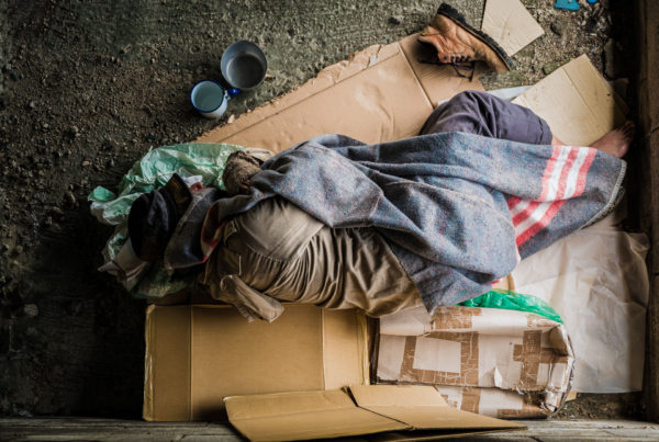 Homeless or indigent person sleeping on cardboard on the streets