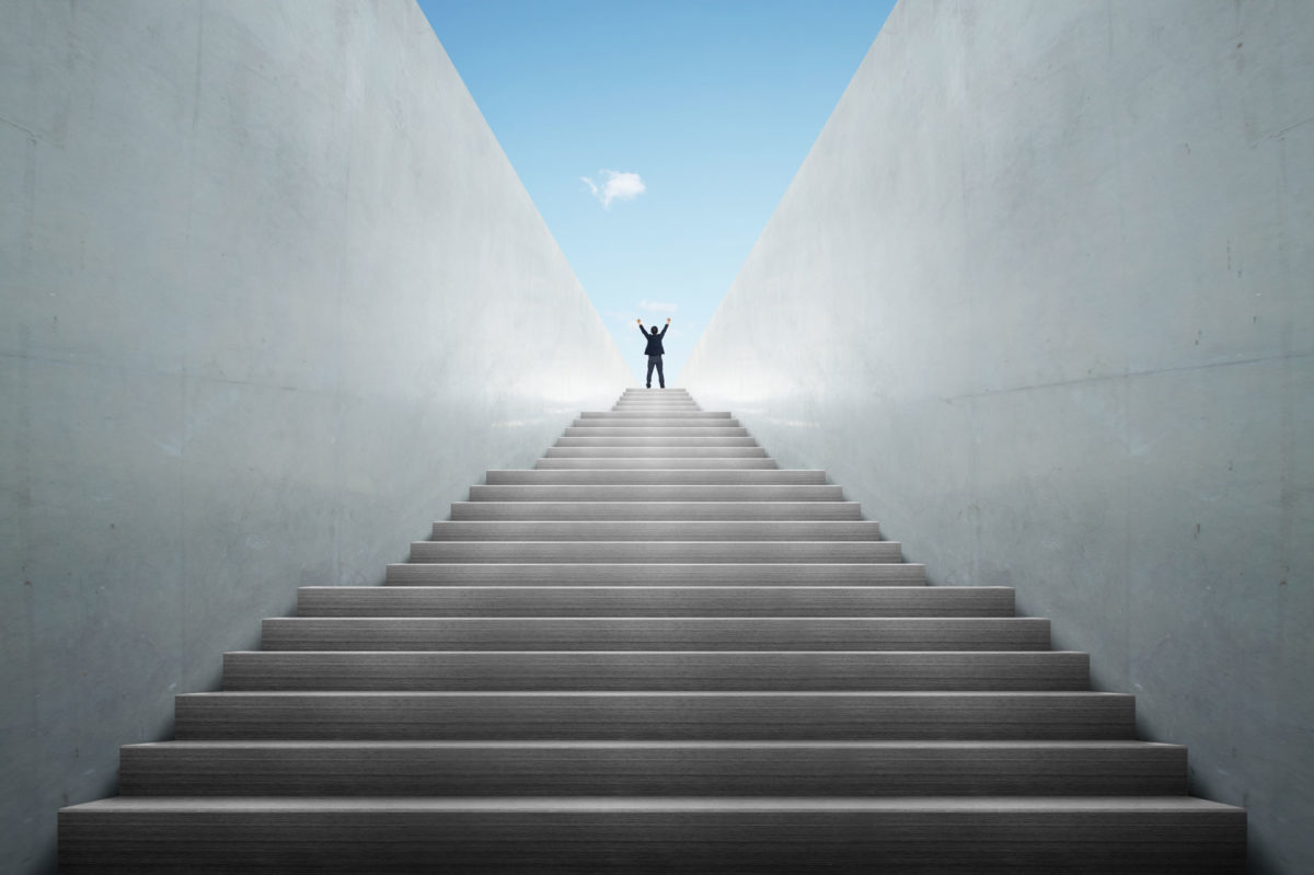 Man cries triumphantly after climbing many stairs as a form of personal growth on the way to financial growth