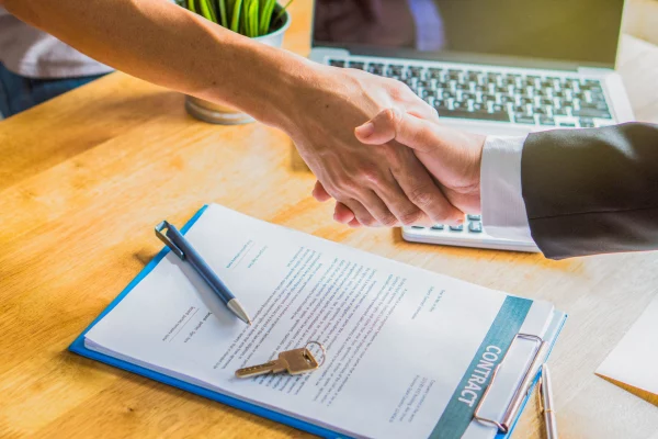 two business owners shake after signing contract to transfer business ownership