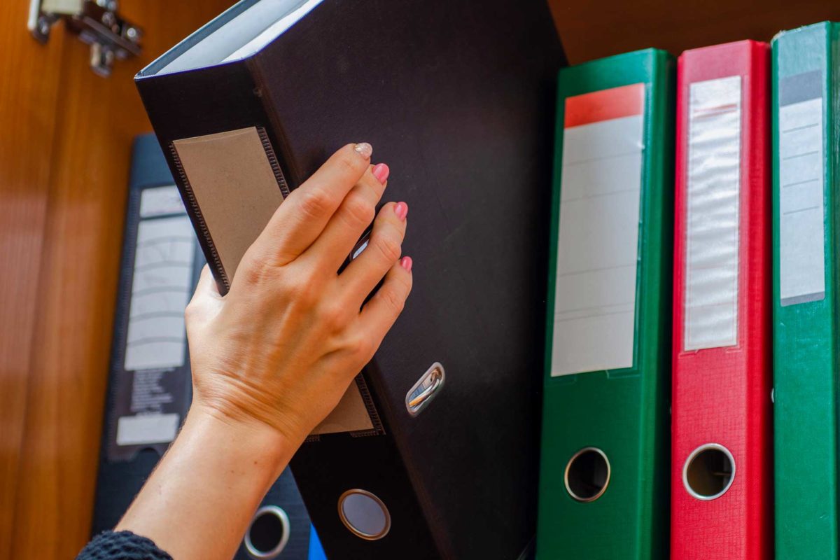 small business owner retrieves business records from bookcase