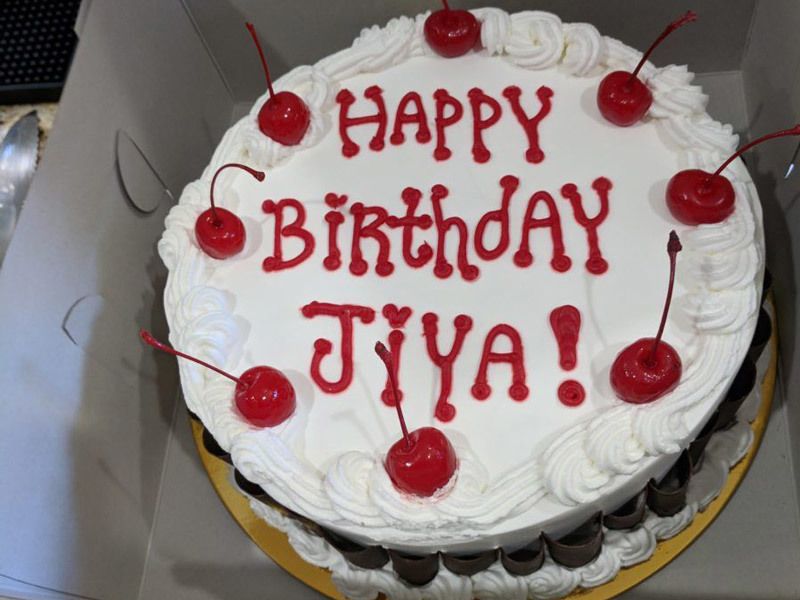 Birthday cake with red and white frosting and cherries.