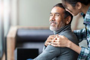 older asian man touching hand on shoulder