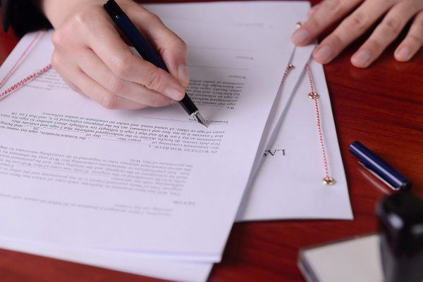 will beneficiary documents being signed on wooden desk