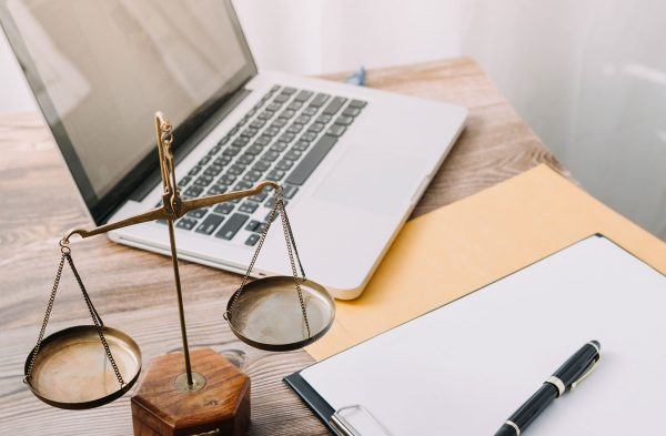 antique legal scales and laptop on desk amid folders and memo pad